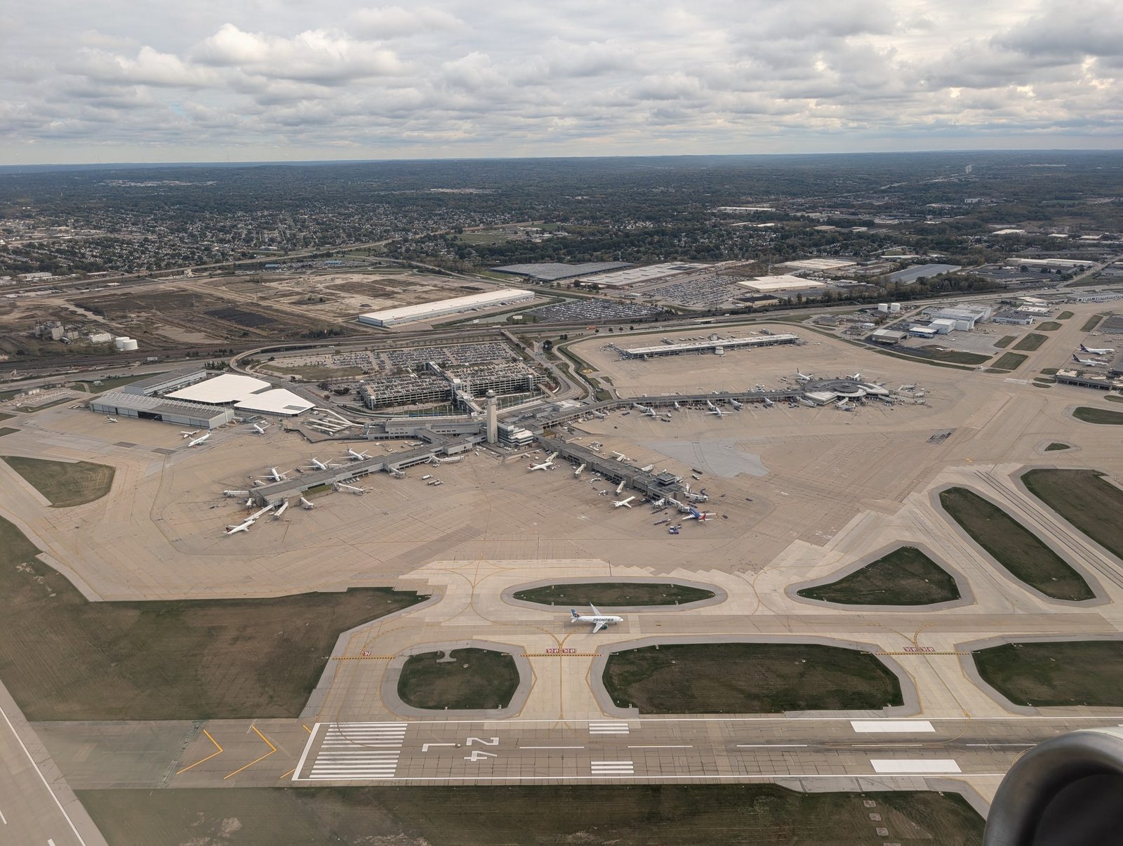 Aerial photograph of the Cleveland Hopkins terminal complex in October 2025: the Main Terminal with Concourses A, B, and C extending from it, apron, parked aircraft, and parking structures